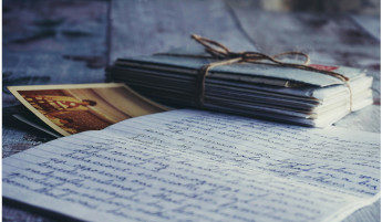 Beschriebenes Blatt im Vordergrund , dahinter verschnürte Briefe